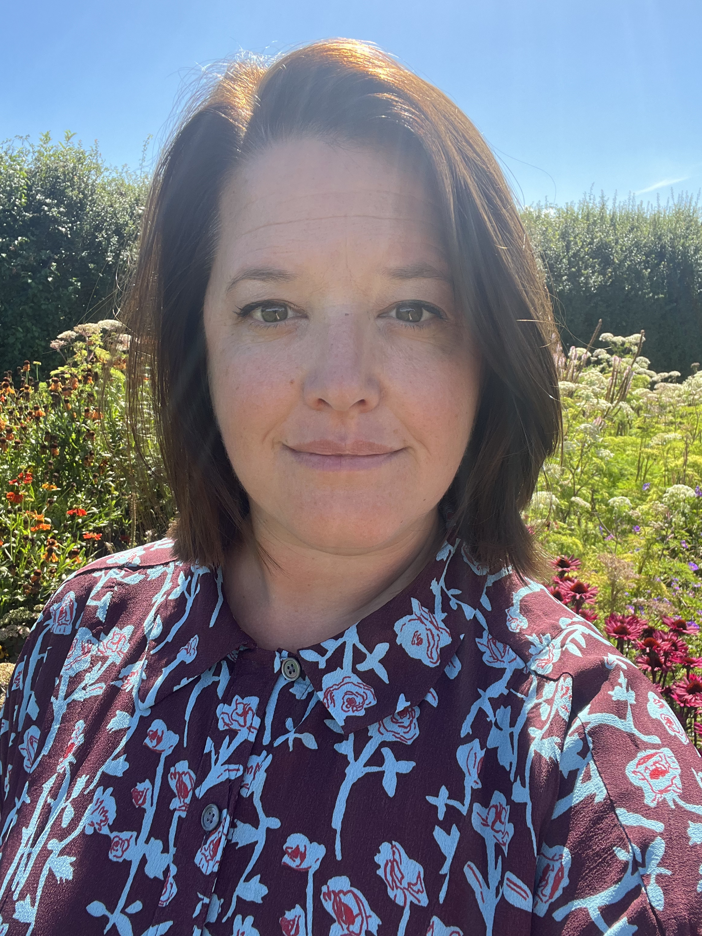 Juliane Caillouette Noble headshot against sunny garden background