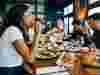 Happy woman eating food at table with other people