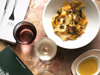 Overhead shot of table with pasta dish, menu and wine glasses at Farmers Marrakech
