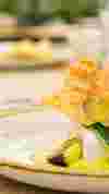 White fish or tofu in bowl with green leafy vegetables and yellow sauce