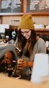 Happy barista in yellow beanie hat making coffee