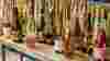 Bottles and glasses of wine on wooden table against flowery curtain