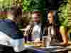 A group of people enjoying a drink together in a sunny Wells & Co. beer garden