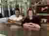 Deano Moncrieffe and Juliane Caillouette Noble sitting at table with arms folded