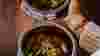 Hands holding two bowls of curry at Lavang