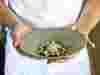 Hands hold a dish of southern calamari at Brae restaurant