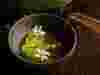 Amber liquid being poured into a bowl of beautiful food against a dark background