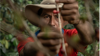 Coffee Producer Norvey Vaquiro wearing a hat, with coffee plant in foreground