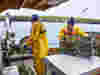 Two men crab fishing on boat wearing yellow waterproof overalls