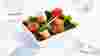 Small square bowl of salad on white surface with napkin and fork